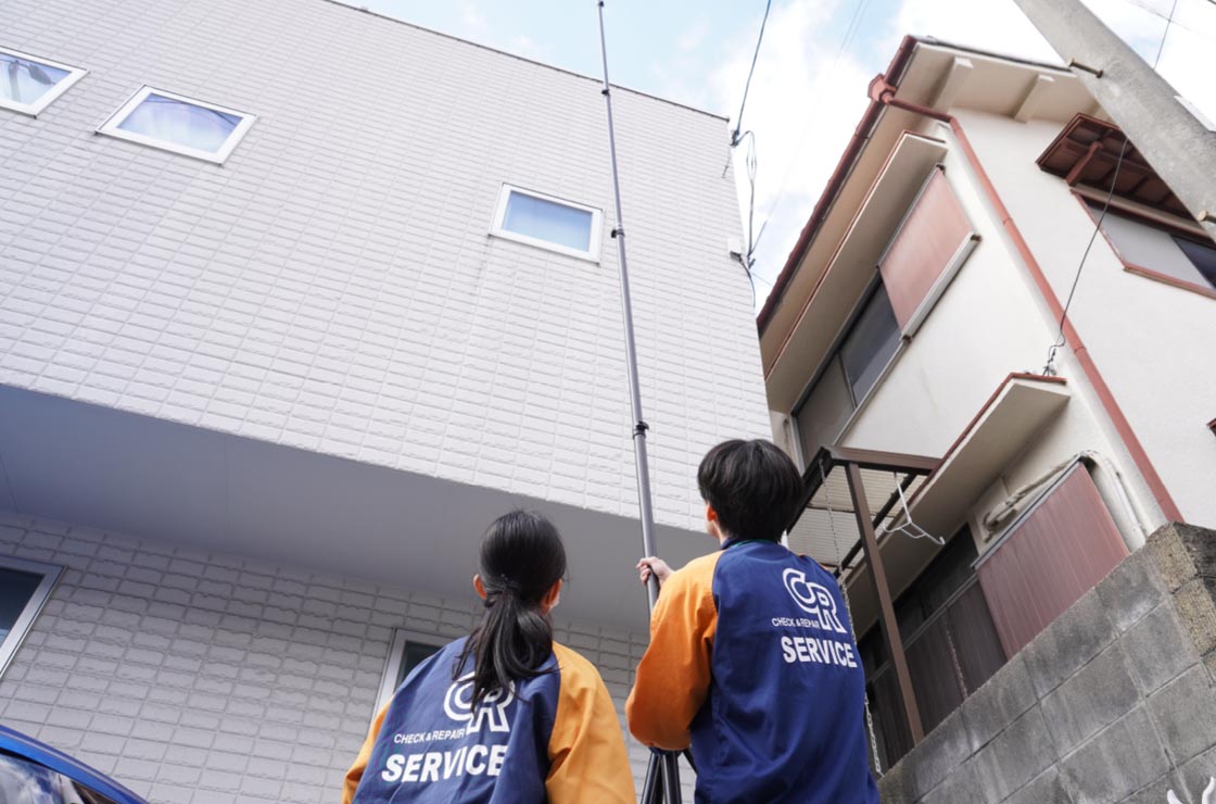 屋根の状態を機械で確認する作業員